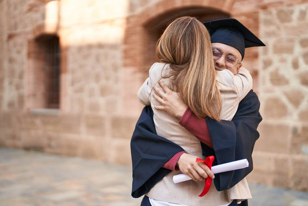 Man and woman mother and son hugging each other celebrating graduation at university - 写真・画像