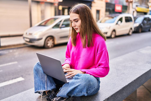 Young woman using laptop sitting on bench at street - Foto, Imagem