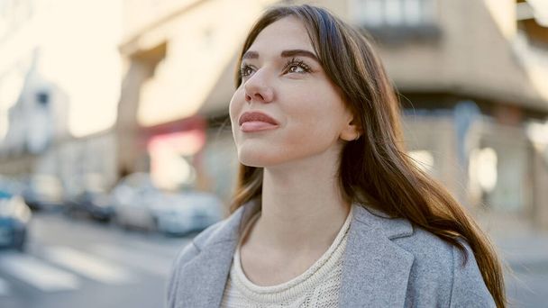 Young hispanic woman standing with serious expression looking to the side at street - Photo, image