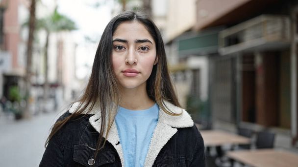 Молодая красивая латиноамериканка, стоящая на улице с серьезным выражением лица - Фото, изображение