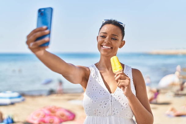 African american woman make selfie by smartphone eating ice cream at seaside - Photo, Image