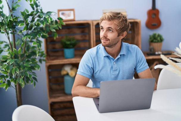 Fiatal férfi használja laptop ül az asztalon otthon - Fotó, kép