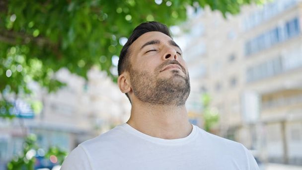 Молодий іспаномовний чоловік дихає закритими очима на вулиці
 - Фото, зображення