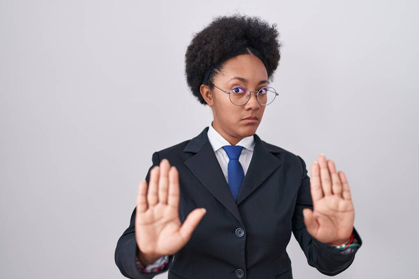 Beautiful african woman with curly hair wearing business jacket and glasses moving away hands palms showing refusal and denial with afraid and disgusting expression. stop and forbidden.  - Photo, Image