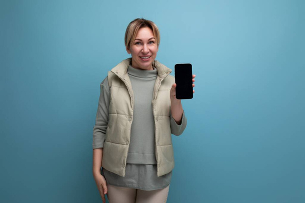Blonde junge Frau zeigt Smartphone-Attrappe. - Foto, Bild