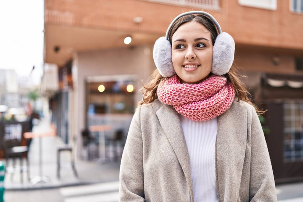 Young beautiful hispanic woman smiling confident wearing scarf and earmuff at street - 写真・画像