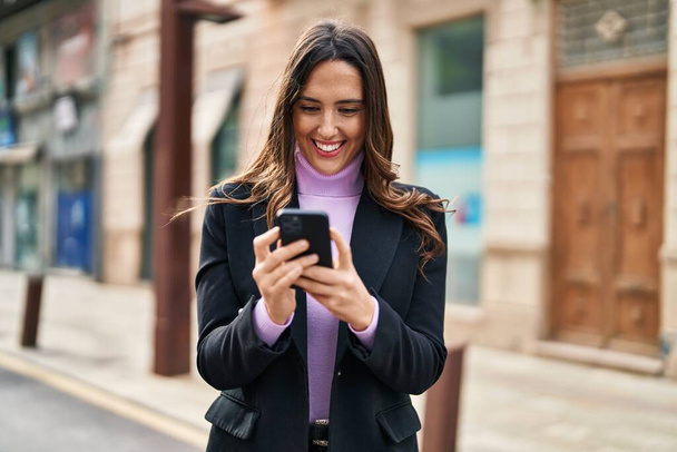 Young hispanic woman smiling confident using smartphone at street - Photo, Image