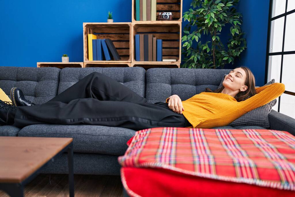 Giovane donna caucasica sorridente fiducioso sdraiato sul divano a casa - Foto, immagini
