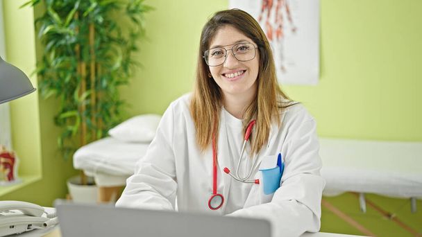 Young blonde woman doctor using laptop working at clinic - Foto, afbeelding