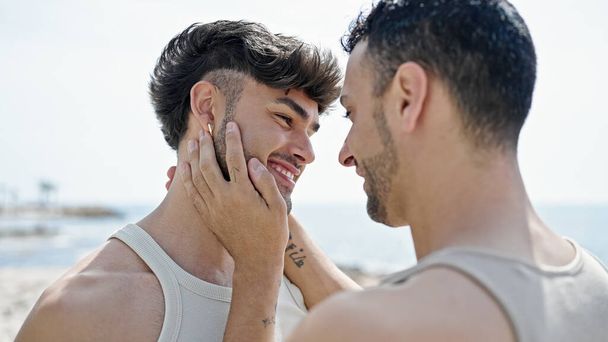 Two men couple smiling confident touching face at seaside - Fotó, kép
