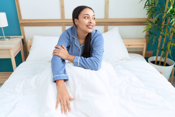 Young arab woman smiling confident sitting on bed at bedroom - Photo, Image