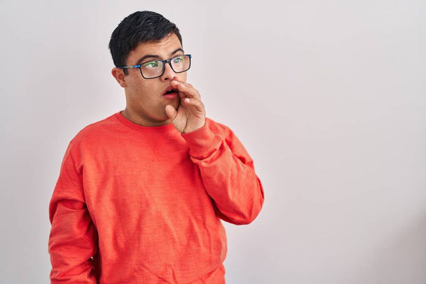 Young hispanic man with down syndrome standing over white background clueless and confused with open arms, no idea and doubtful face.  - Photo, Image