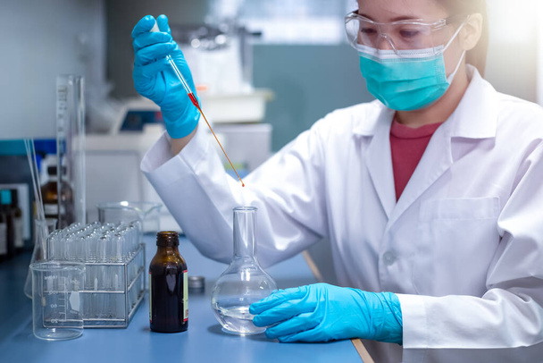 Chemical Advanced Research Laboratory, the female scientist is adding a reagent for the chemical preparation of the experiment in the lab. Research for pharmaceutical, medicine, and biotechnology development - Foto, afbeelding
