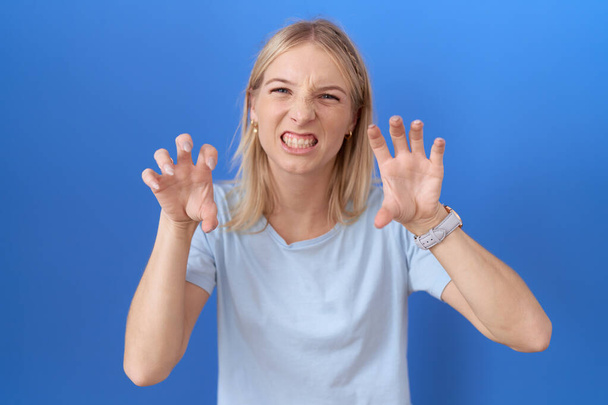 Young caucasian woman wearing casual blue t shirt smiling funny doing claw gesture as cat, aggressive and sexy expression  - Foto, Imagen