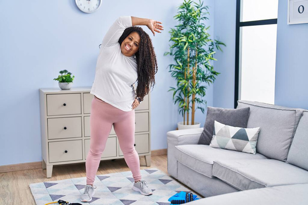 African american woman smiling confident stretching back at home - Photo, Image