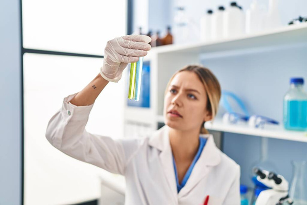 Young hispanic woman scientist holding test tubes at laboratory - Photo, Image