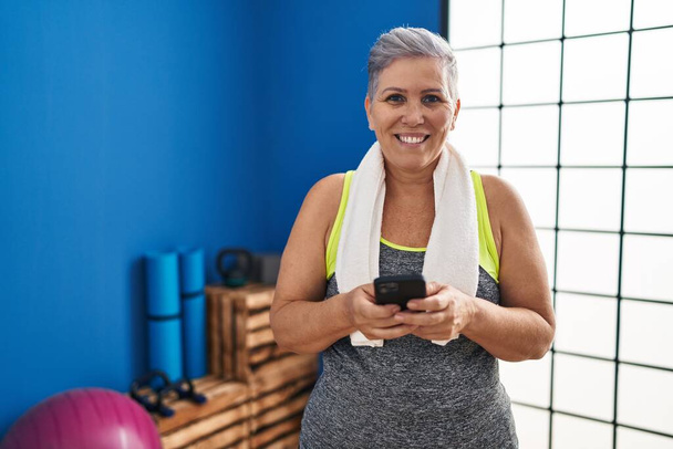 Middle age woman wearing sportswear using smartphone at sport center - Foto, Imagen
