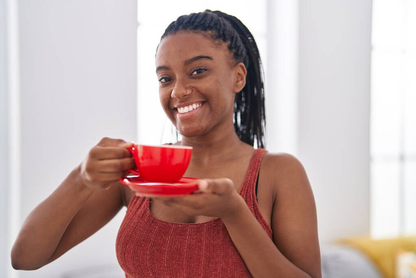 Africano americano mulher sorrindo confiante beber café em casa - Foto, Imagem