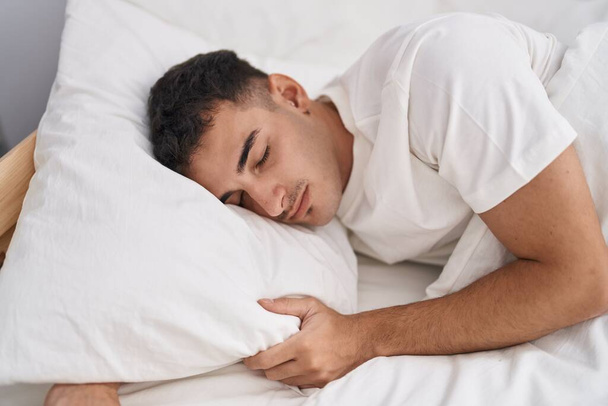 Young hispanic man lying on bed sleeping at bedroom - Foto, Imagem