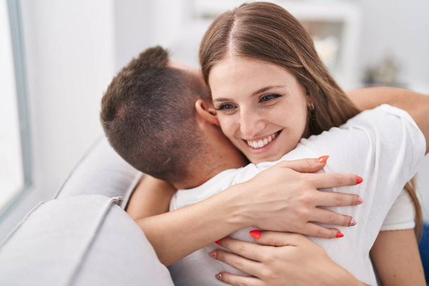 Homem e mulher casal abraçando uns aos outros sentado no sofá em casa - Foto, Imagem