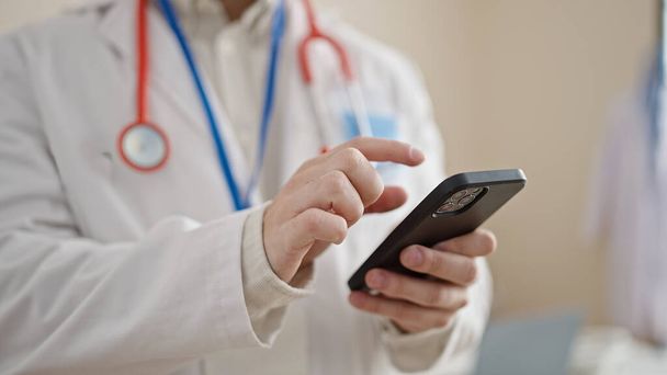 Young hispanic man doctor using smartphone at clinic - Foto, immagini