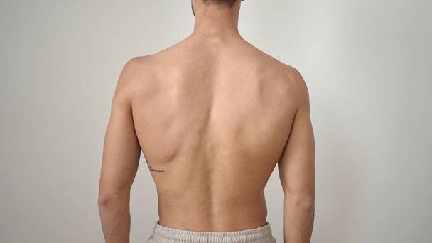 Young hispanic man standing on back view over isolated white background - 写真・画像