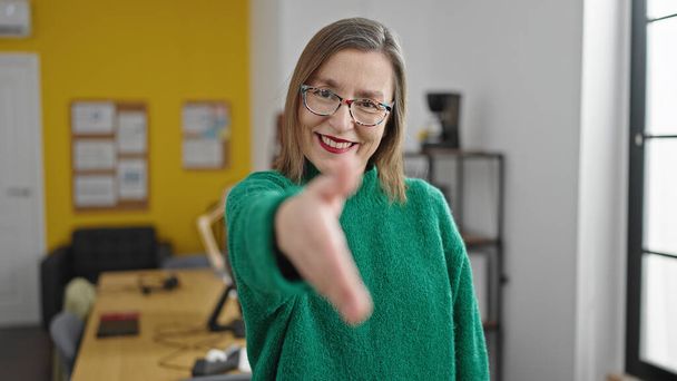 Mature hispanic woman with grey hair smiling confident offering handshake at office - Zdjęcie, obraz