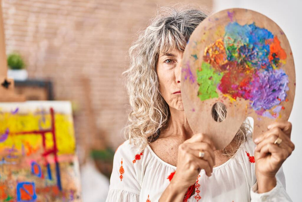 Žena středního věku drží malířskou paletu zakrývající tvář sklíčenou a strachující se o úzkost, pláče vzteky a strachem. smutný výraz.  - Fotografie, Obrázek