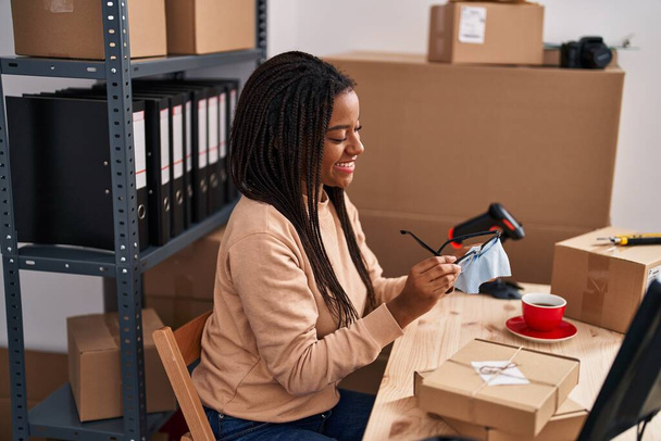 African american woman ecommerce business worker cleaning glasses at office - Photo, Image