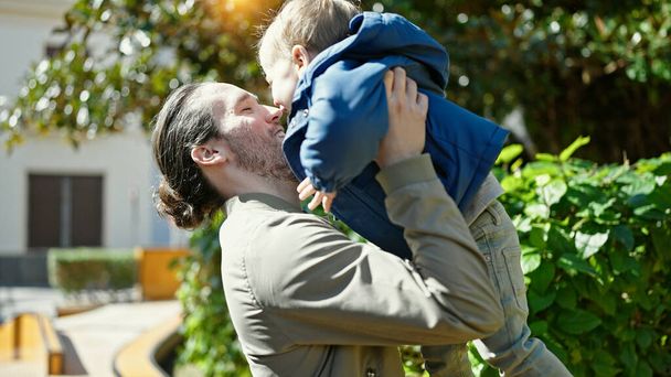 Padre e figlio sorridono fiduciosi abbracciandosi al parco - Foto, immagini