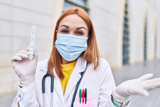 Fiatal orvos nő gazdaság coronavirus fertőzés teszt ünneplő eredmény boldog mosollyal és győztes kifejezés emelt kézzel  - Fotó, kép