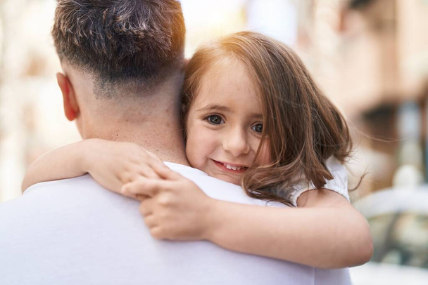 Père et fille souriant confiants se serrant dans leurs bras au parc - Photo, image