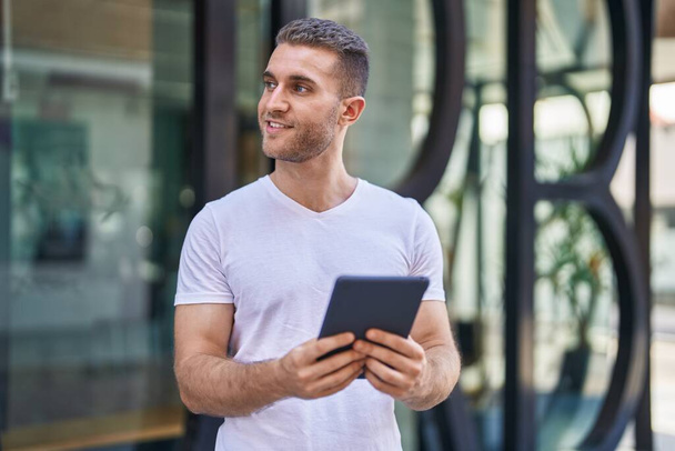 Young caucasian man smiling confident using touchpad at street - Photo, Image