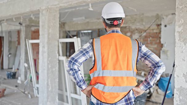 Middle age man builder standing backwards at construction site - Fotó, kép