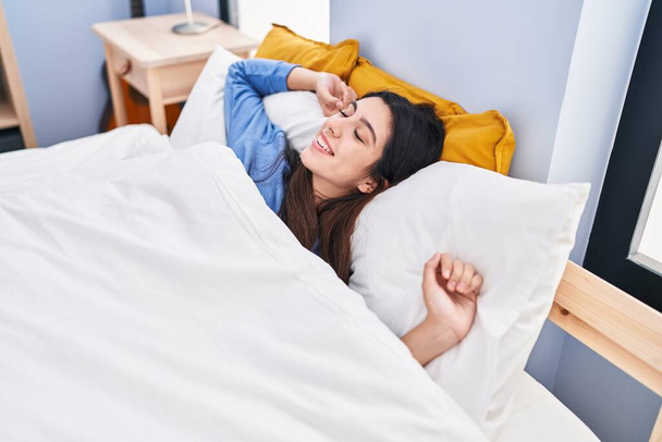 Молодая красивая латиноамериканка просыпается с протянутыми руками в спальне - Фото, изображение