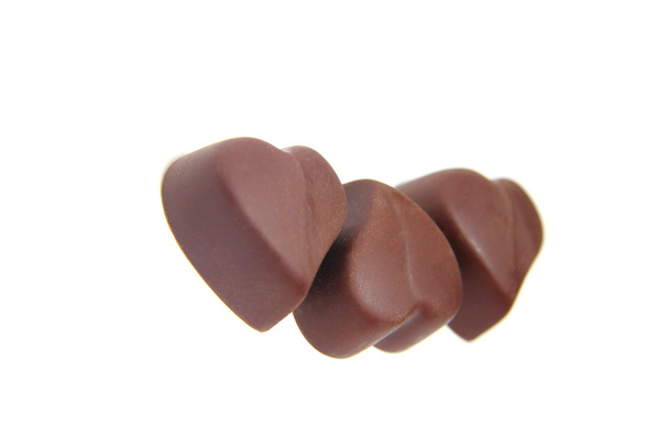 Три шоколадні цукерки у формі серця на білому тлі
 - Фото, зображення