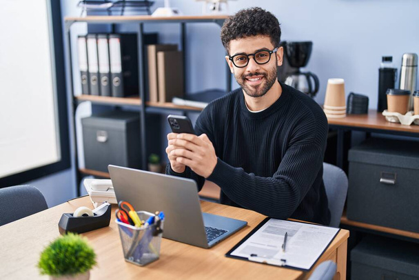 Молодой арабский бизнесмен использует смартфон, работающий в офисе - Фото, изображение