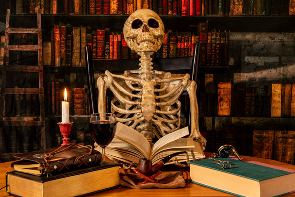 squelette assis dans la bibliothèque de recherche rétro livre de lecture par bougie avec verre de vin - Photo, image