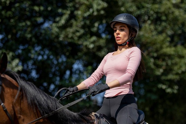 Jinete femenino con casco montado en un caballo en un centro ecuestre - Foto, Imagen