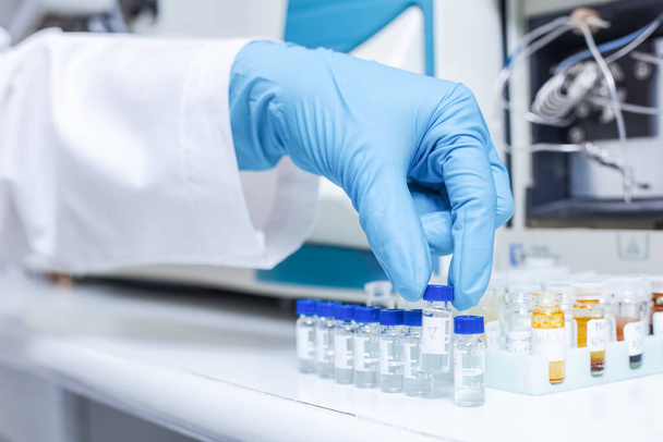 A hand of scientists arrange vials of samples in order of sample or prepare samples for analysis by Liquid Chromatography mass spectrometry LC-MS analysis in the lab. LC-MS is used for scientific research. - Photo, Image