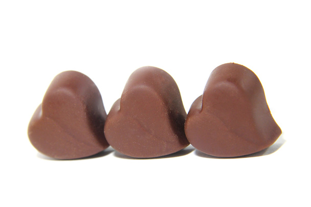 Три шоколадні цукерки у формі серця на білому тлі
 - Фото, зображення