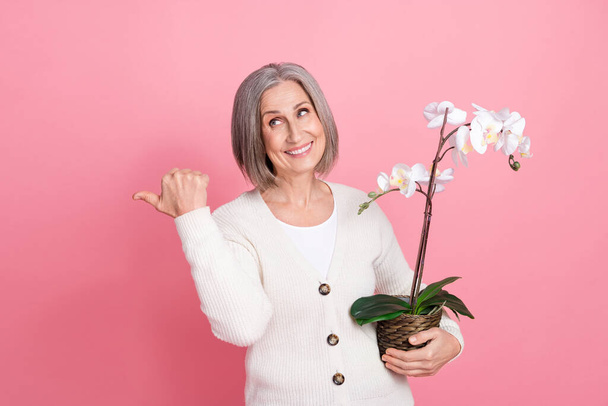 Full size photo of attractive senior woman point look empty space orchid dressed stylish white clothes isolated on pink color background. - Photo, Image