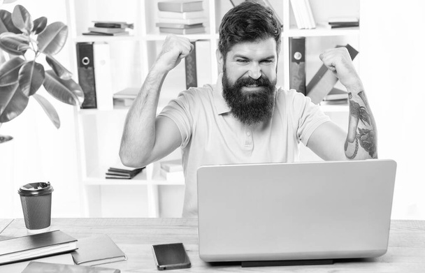 Excited man making winning gesture looking in laptop at office desk, business success. - Foto, immagini