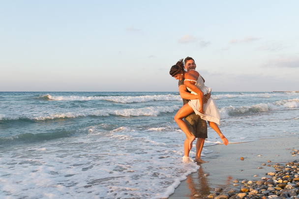 若いカップルは、夕暮れ時にかすんでいるビーチの上を歩いて楽しむ. - 写真・画像