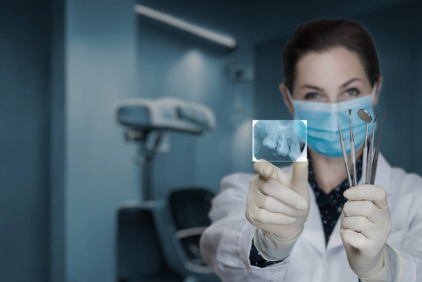 The doctor shows a picture of dental treatment on a blurred background. - Photo, Image