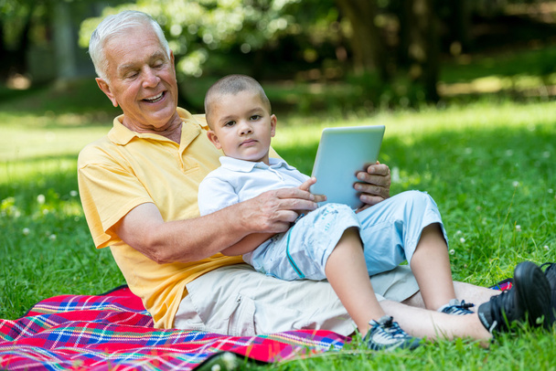 Grandfather and child in park using tablet - Fotó, kép