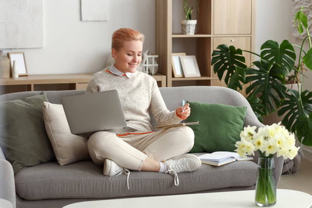 Female student studying with laptop on sofa at home - Foto, Bild