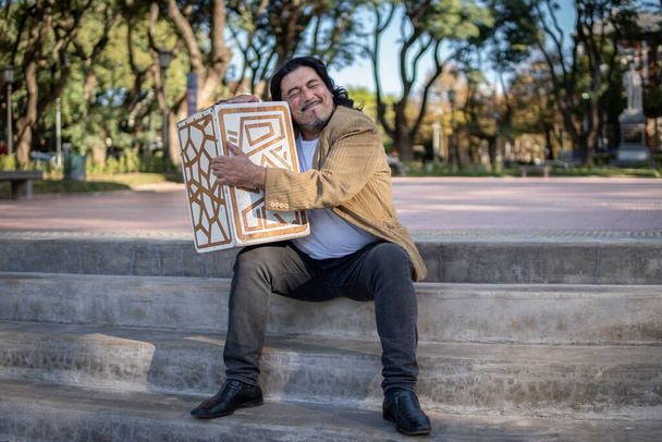 İspanyol müzisyen parkta oturmuş flamenko kutusuna sarılıyor. - Fotoğraf, Görsel