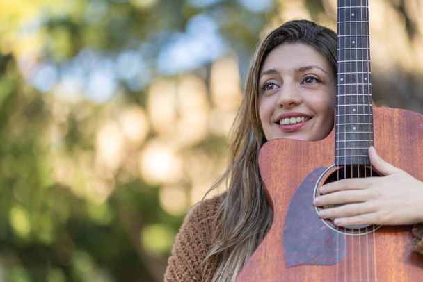 Mujer rubia joven con su guitarra en el parque. Concepto de afición creativa y profesionales. Actitud positiva. Empoderamiento. - Foto, imagen