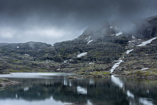 Reflection over a lake in moody vibe in the hike for Trolltunga, Norway - 写真・画像